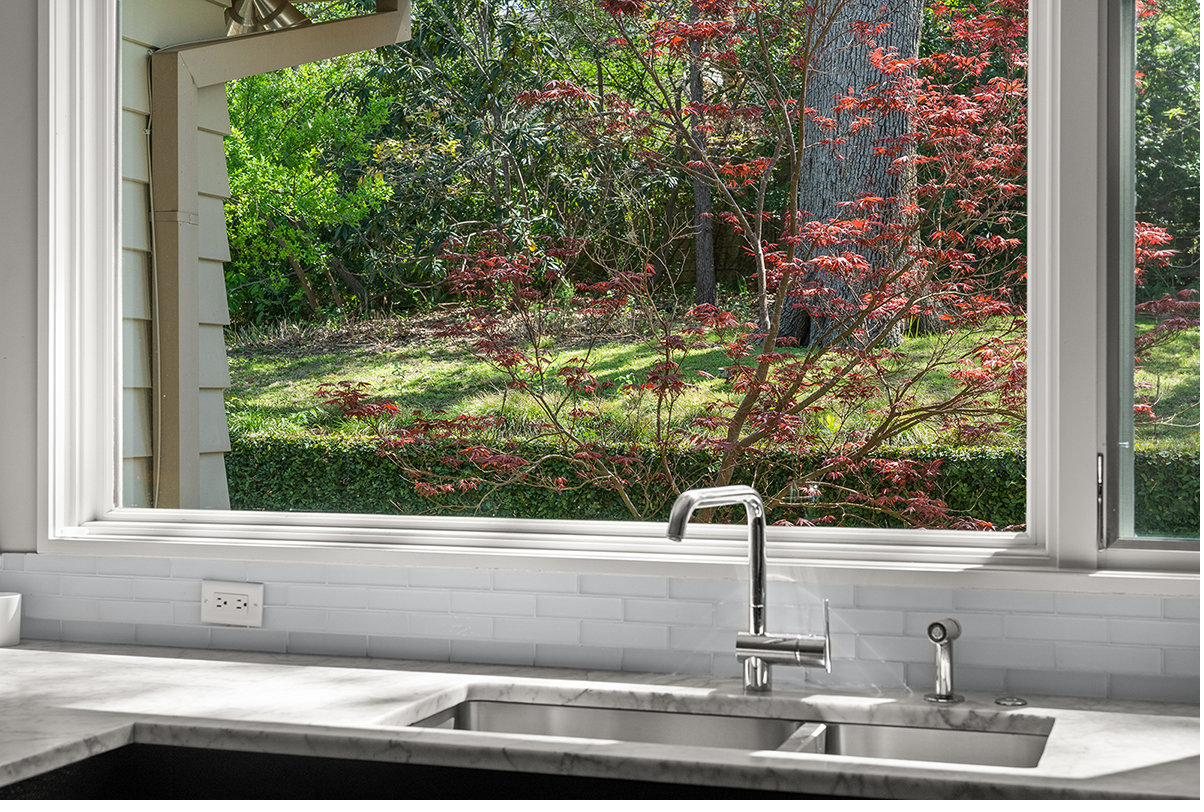 Casement window above the sink framing a Japanese maple