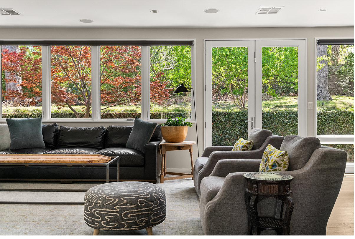 Family room with leather seating and wall of windows onto Japanese maples