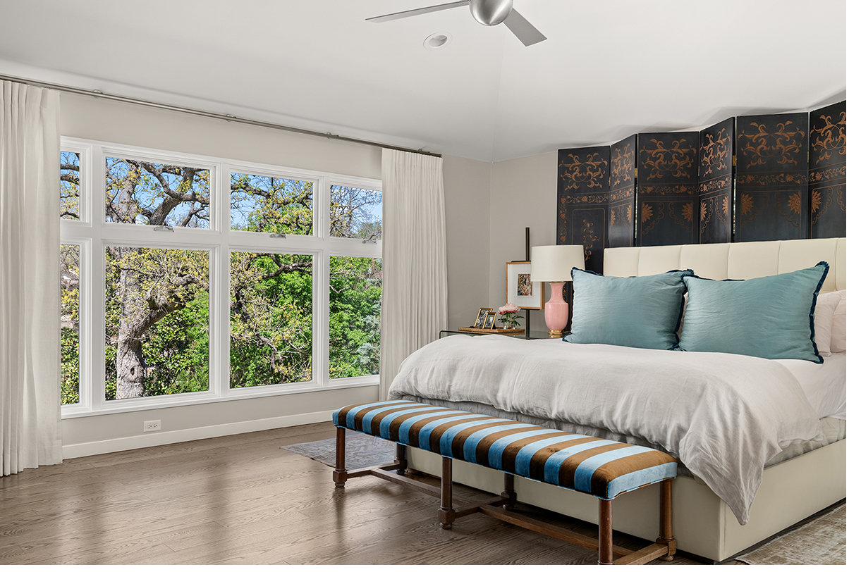 Primary bedroom with antique chinoiserie screen and treetop windows